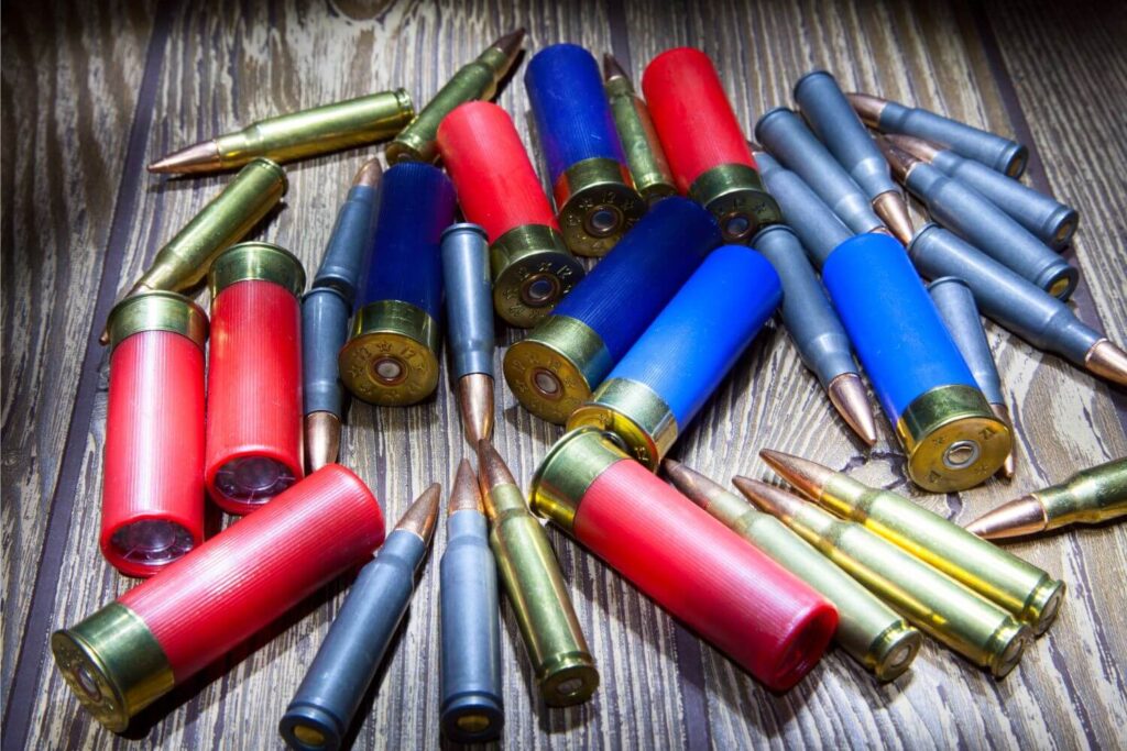 A variety of bullets sitting in a pile on a wooden table