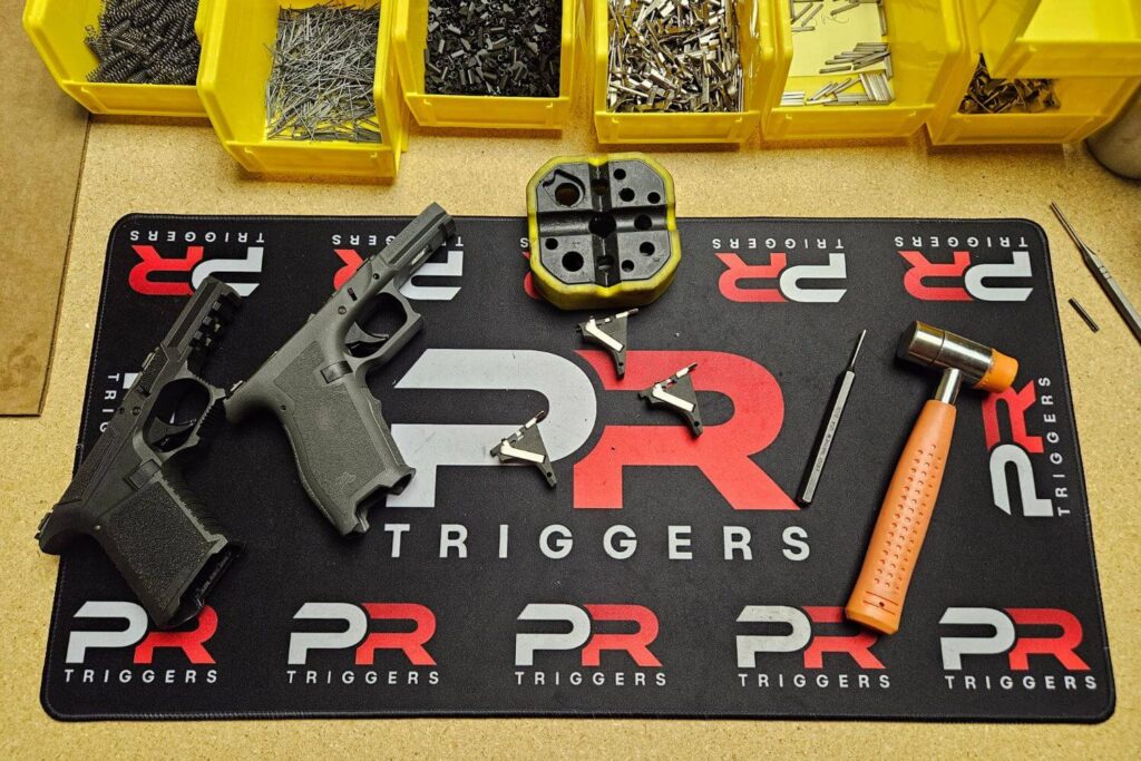 multiple disassembled pistols and PR Triggers Model G components on a workmat