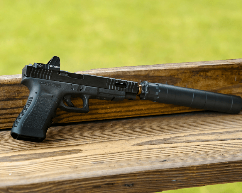 A glock pistol with various aftermarket upgrades sitting on a wooden shelf
